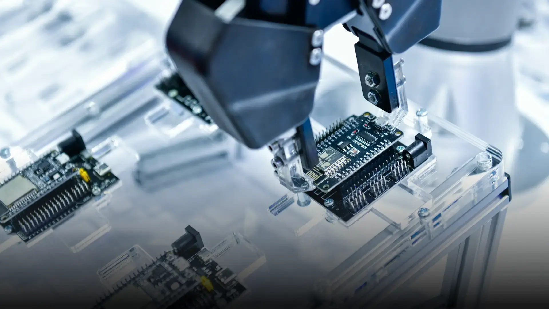 Robotic arm positioned above a circuit board in a laboratory, representing electronics assembly, inspection, and advanced robotics.
